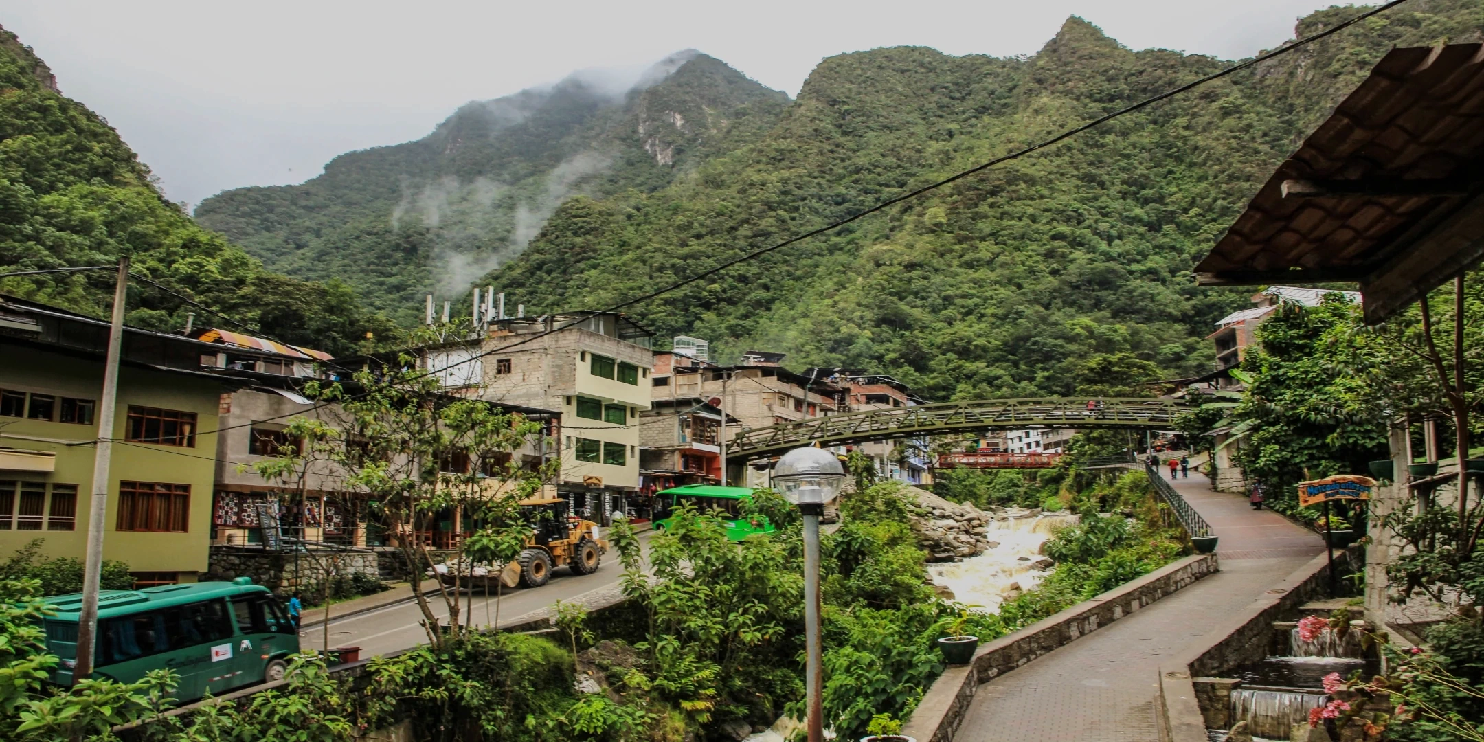 Panoramic view of Aguas Calientes town surrounded by lush green mountains and the Vilcanota river.