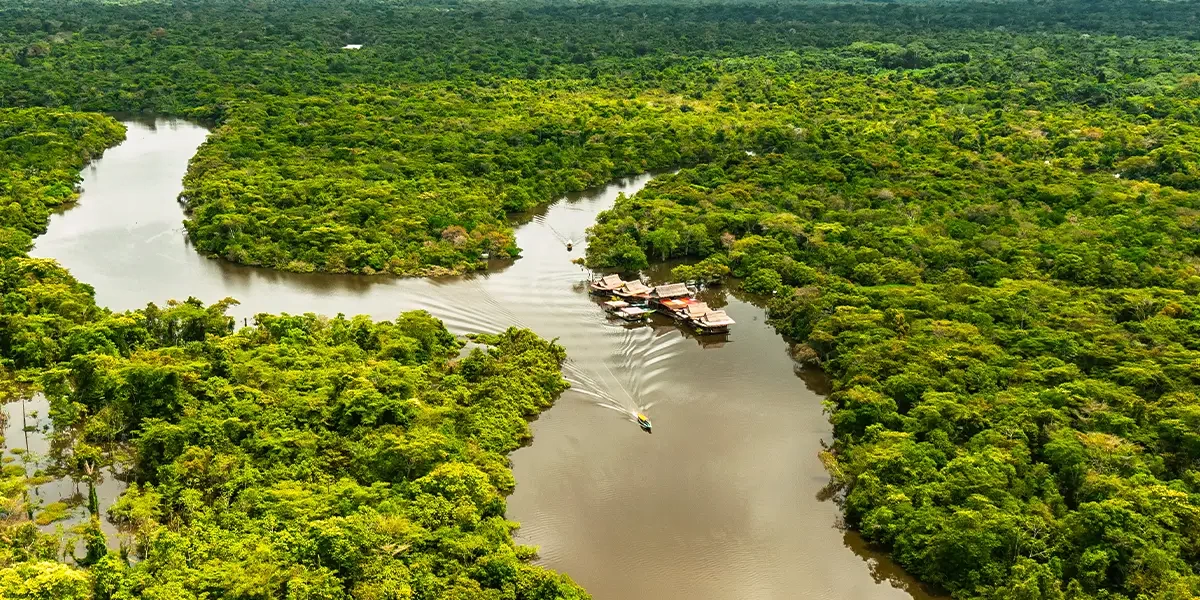Aerial view of eco-lodges and traditional floating houses along a wide river in the Peruvian Amazon
