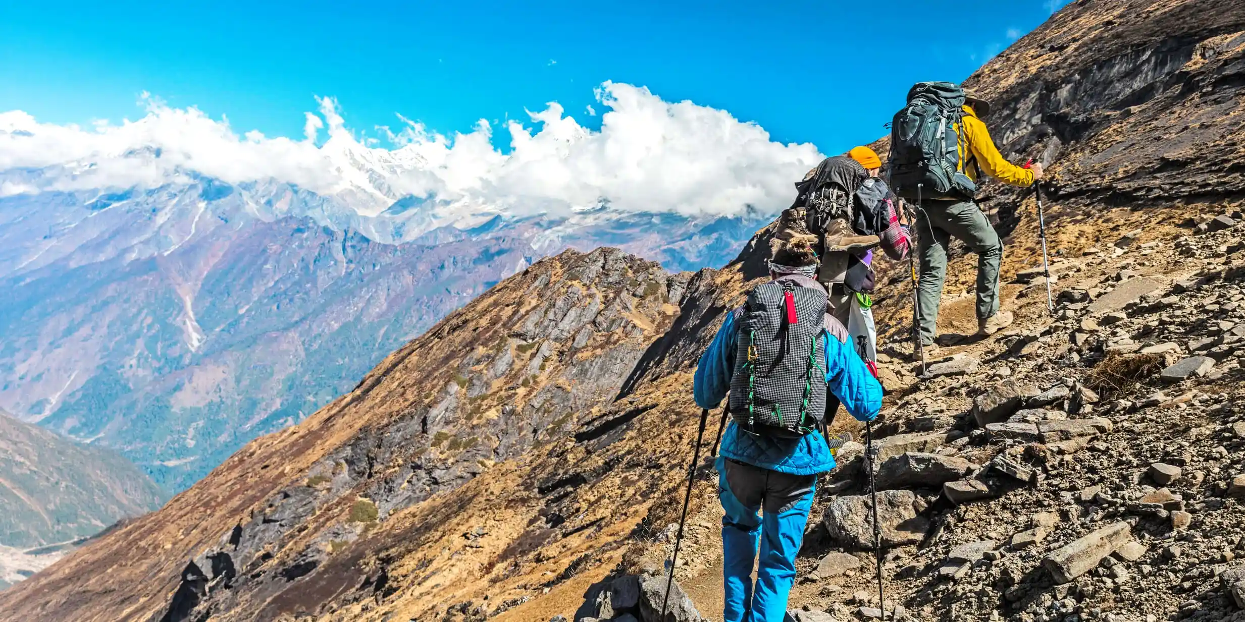 Group of trekkers with hiking poles climbing a rocky mountain path in the Annapurna region of Nepal.