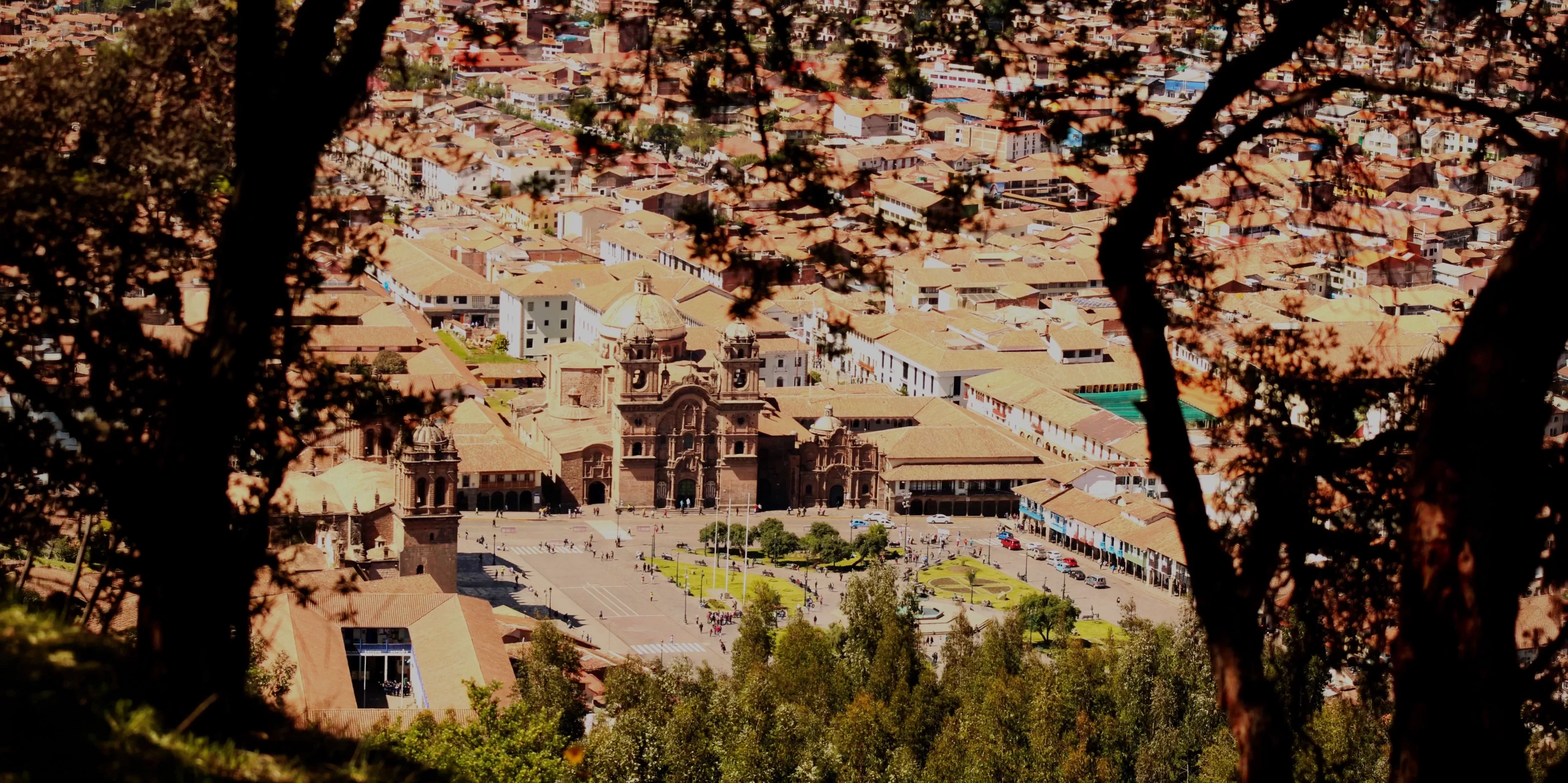 High angle view of Cusco's Plaza de Armas and the Cathedral framed by trees.