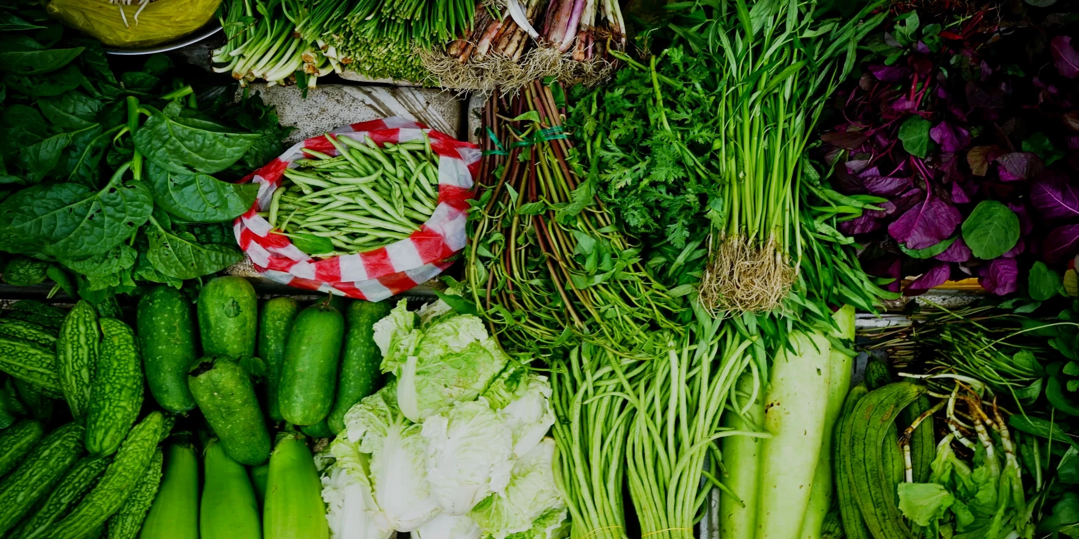 A vibrant top-down view of fresh organic vegetables including greens, beans, and local produce at a traditional Peruvian market.