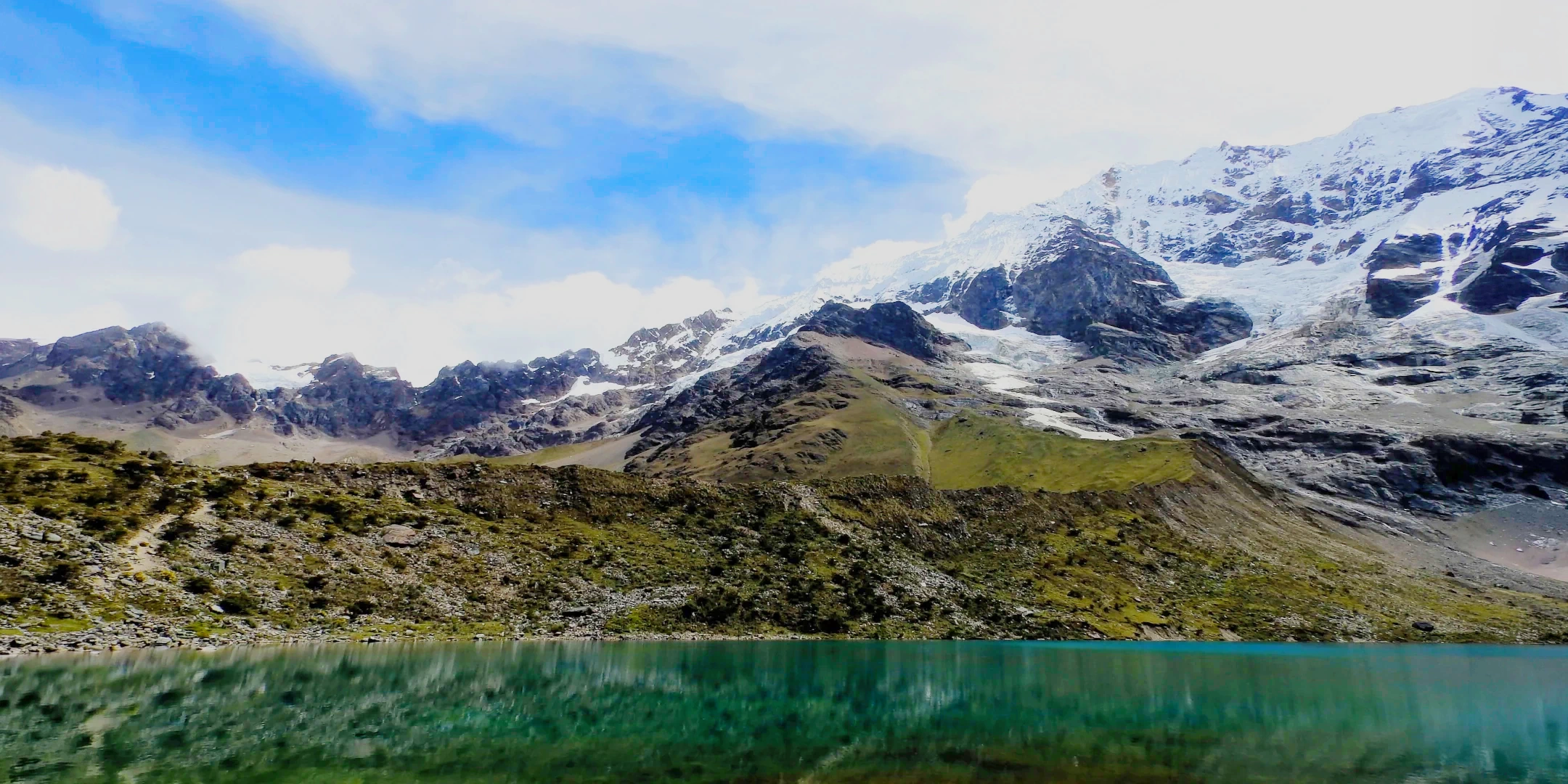 Scenic landscape of the Vilcabamba mountain range with glaciers and green slopes above the Humantay Lake.