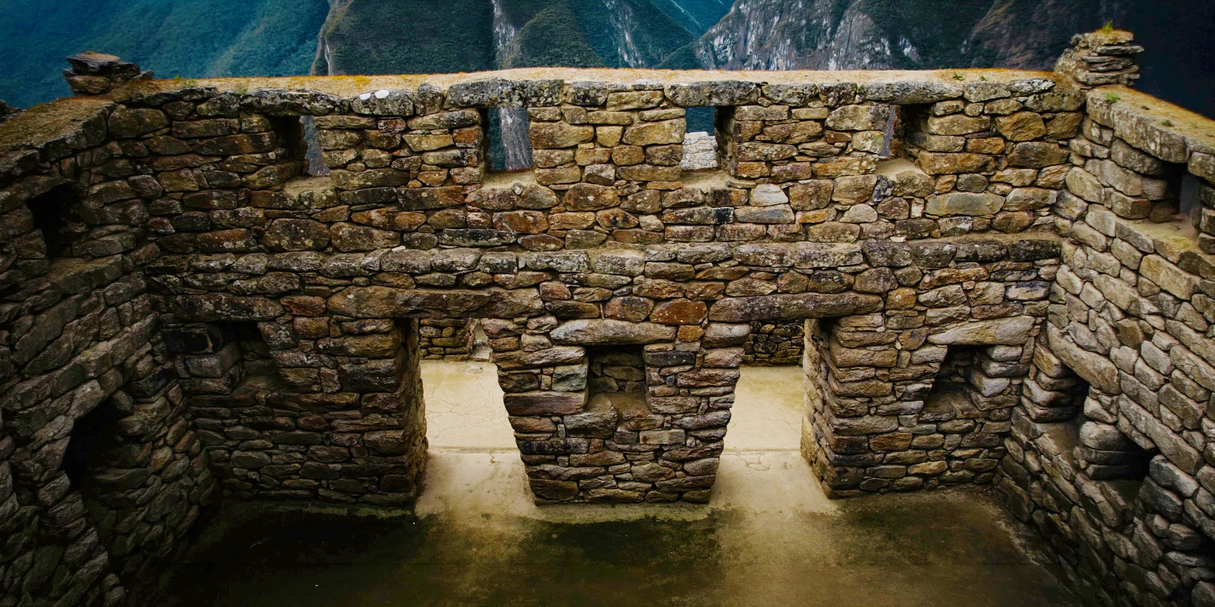 Close-up of ancient Incan stone masonry featuring trapezoidal windows overlooking the Andean mountains.