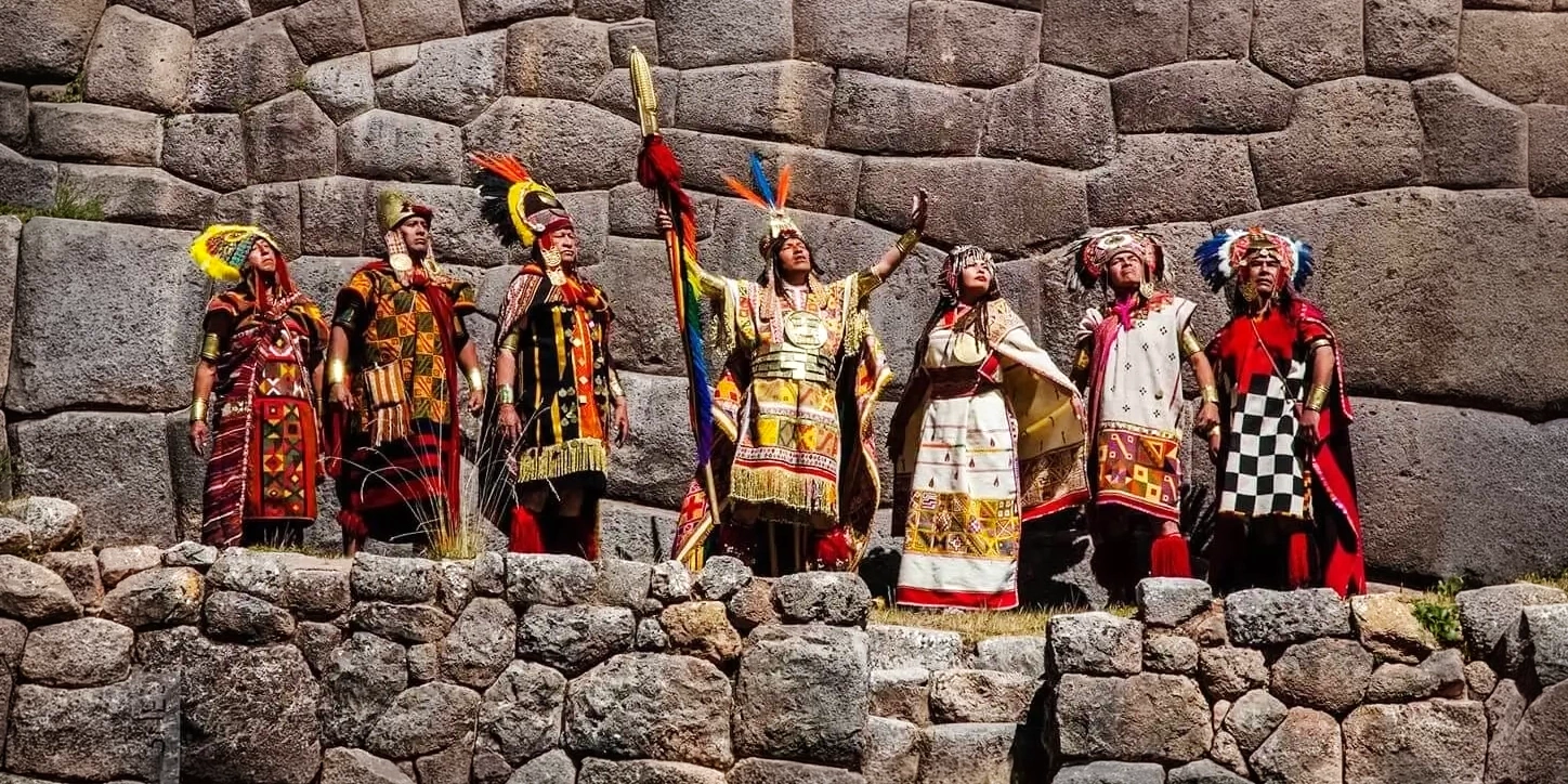 A group of actors dressed as Inca royalty performing a ceremony in front of the stone walls of Sacsayhuaman.