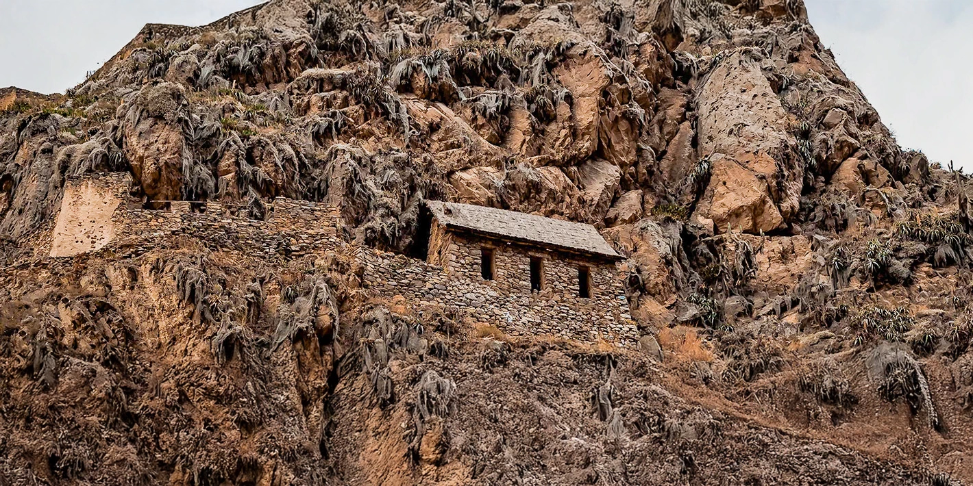 Ancient Incan stone storehouses (qollqas) built on a steep rocky mountainside in the Sacred Valley.