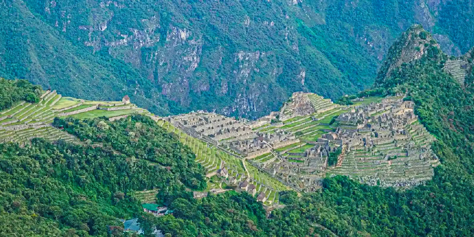 Wide aerial view showing the full extent of the Machu Picchu archaeological complex nestled in the mountains.