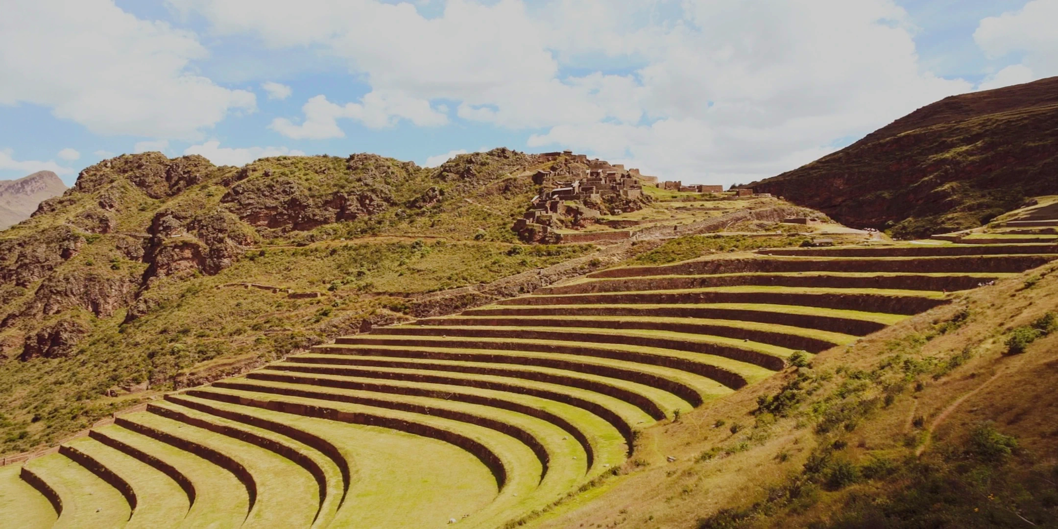 Wide view of the impressive circular agricultural terraces of Pisac with the Andes mountains in the background.