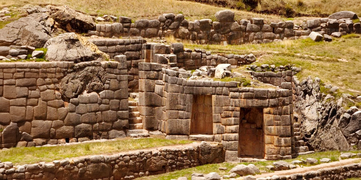Full panoramic view of the Tambomachay site showing the grand stone walls and the surrounding Andean landscape.