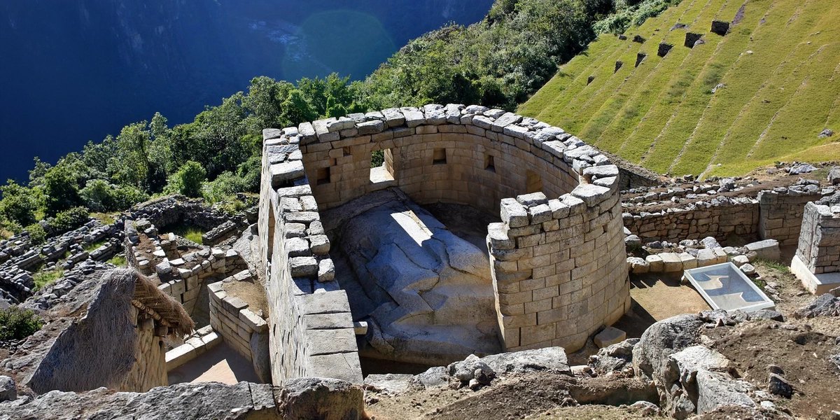 High-angle view of the semi-circular Temple of the Sun at Machu Picchu, featuring its distinctive curved walls and sacred windows overlooking the terraces.