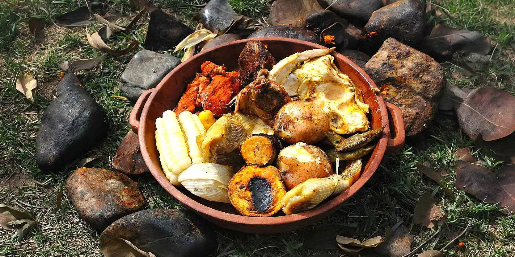 A clay bowl filled with traditional Peruvian Pachamanca including corn, potatoes, fava beans, and various meats cooked underground