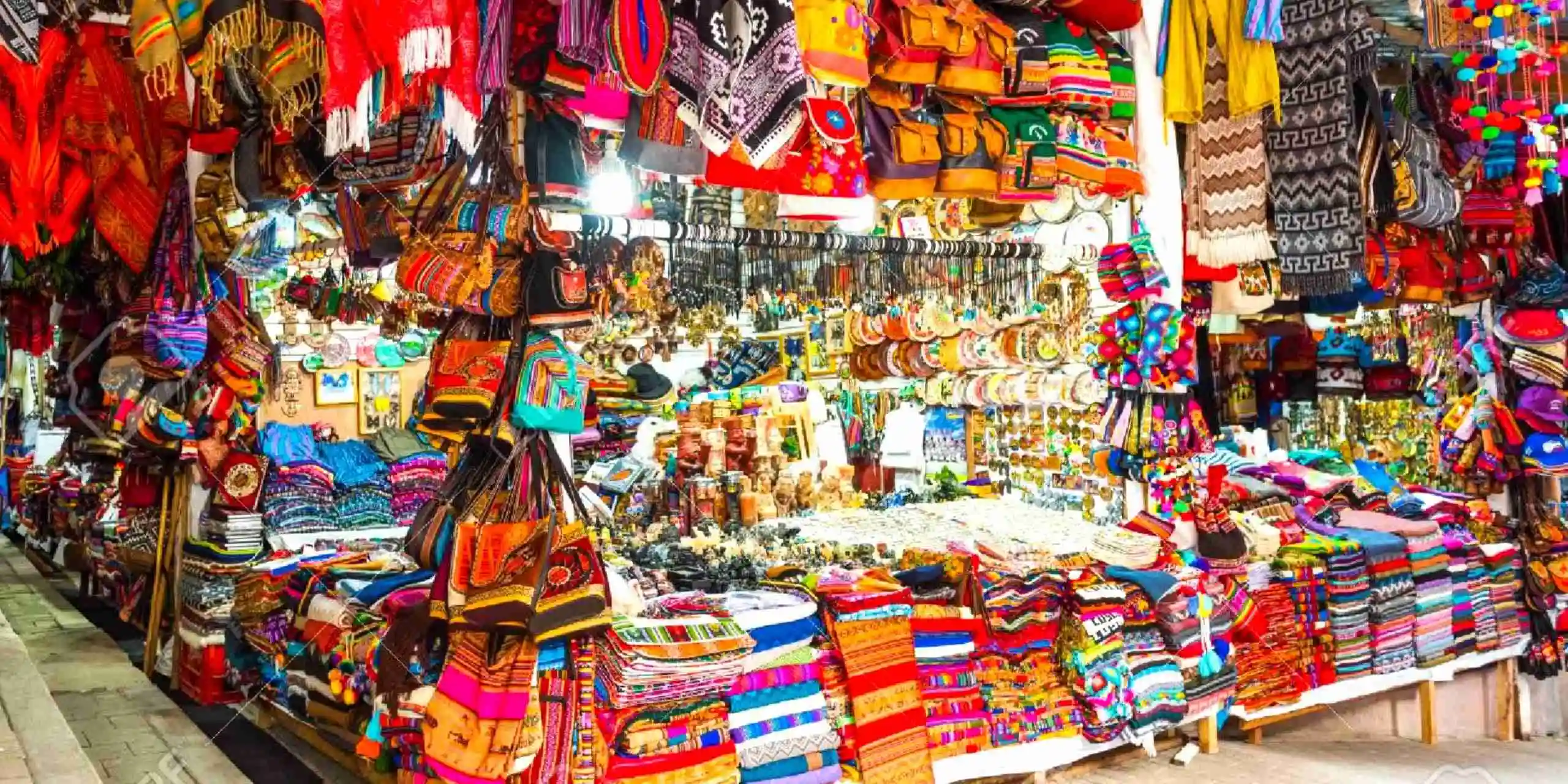 A colorful market stall in Aguas Calientes filled with traditional Andean bags, textiles, and handcrafted souvenirs