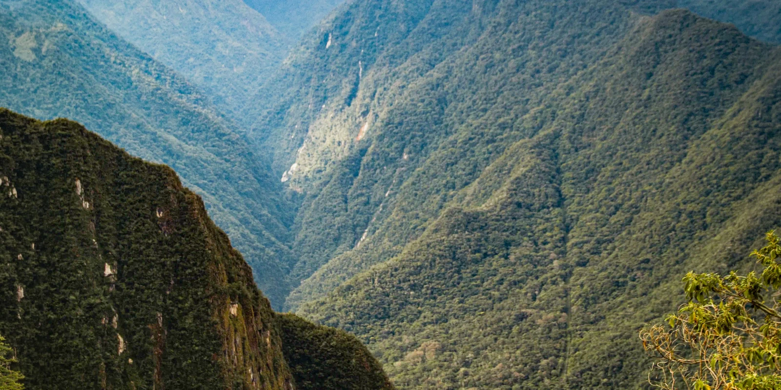 Panoramic landscape of lush green mountains and deep valleys along the trek to Wiñay Wayna.