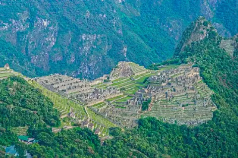 A broad panoramic landscape of the Machu Picchu citadel and its surrounding lush green mountains.
