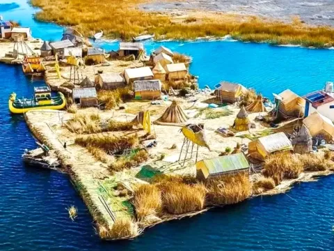 An aerial perspective of a complete floating island community in Uros, showing totora houses and reed structures.