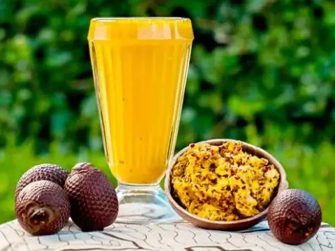 A glass of fresh Aguajina juice served with aguaje palm fruits on the side.