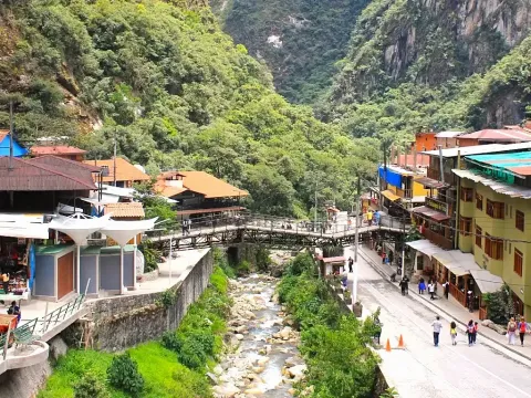 Urban landscape of Aguas Calientes featuring pedestrian bridges crossing the river surrounded by lush cloud forest vegetation