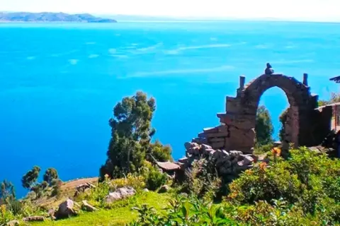 A stone arch on a hill at Amantani Island surrounded by green vegetation with a panoramic view of the lake.