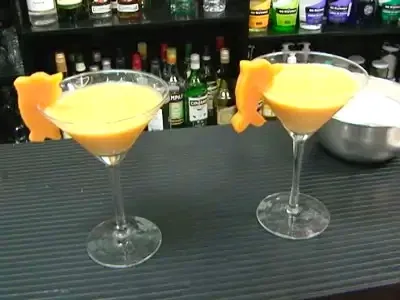 Two glasses of Camote Sour cocktail garnished with sweet potato slices on a bar.