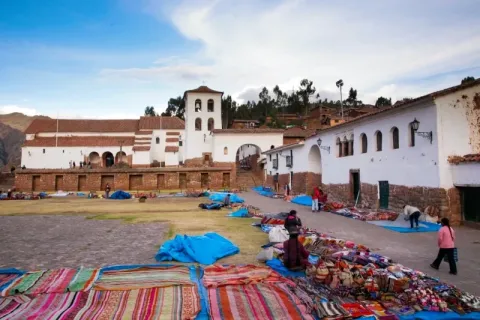 Local artisans selling colorful Andean textiles in front of the colonial church in Chinchero, Sacred Valley.