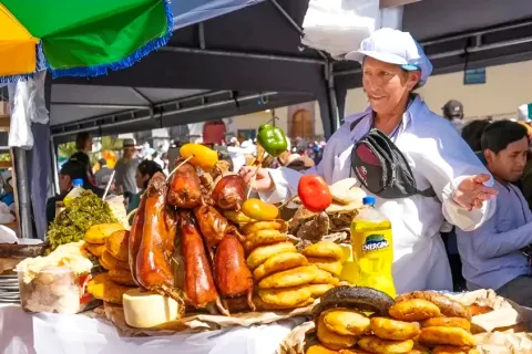 A local woman at a traditional food stall in Cusco preparing and serving large plates of Chiriuchu.