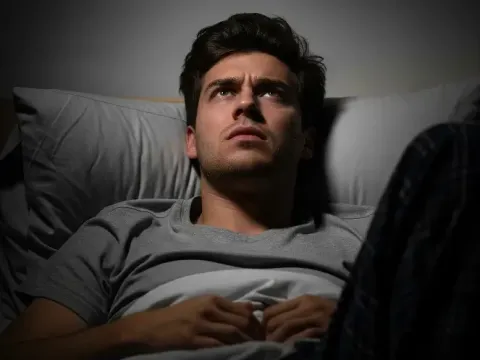 Man lying in bed looking at the ceiling, illustrating difficulty sleeping as an effect of high altitude adjustment