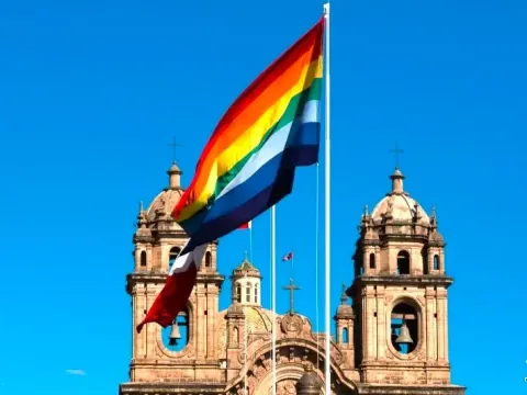 Seven-striped flag of Cusco flying in front of the Baroque façade of the Church of the Society of Jesus