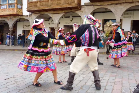 Couples dancing Huayno in traditional colorful skirts (polleras) at the Plaza de Armas in Cusco.