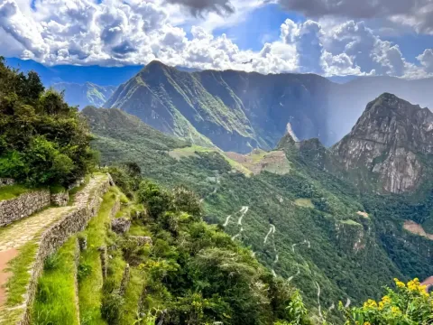Scenic stone path on the Inca Trail overlooking green mountains and clouds.