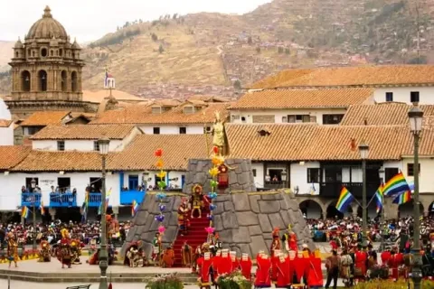 Panoramic view of the Inti Raymi ceremony in Cusco's Plaza de Armas with colonial churches in the background.