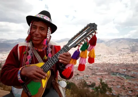 Man in traditional costume playing the charando, enjoying the sound of this instrument. 