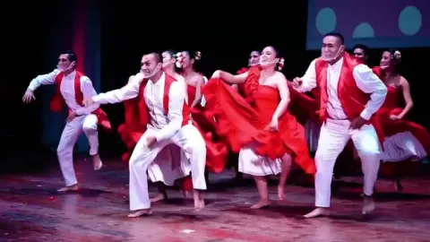 Women and men dancing the traditional Festejo dance wearing red and white costumes simulating the national flag of Peru.