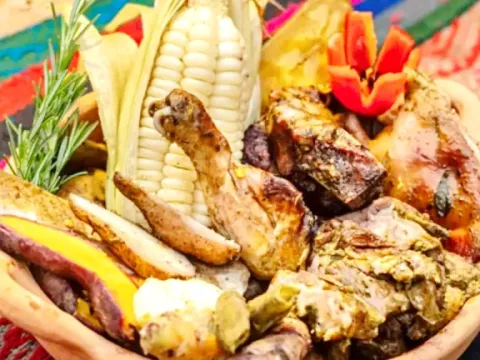 A close-up of a clay pot with chicken, corn, and sweet potatoes served over a colorful traditional Andean woven fabric