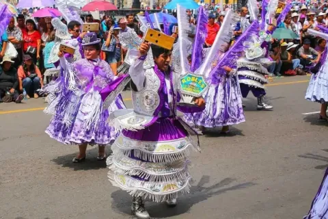 Men and women dancing in colorful costumes in a traditional parade.