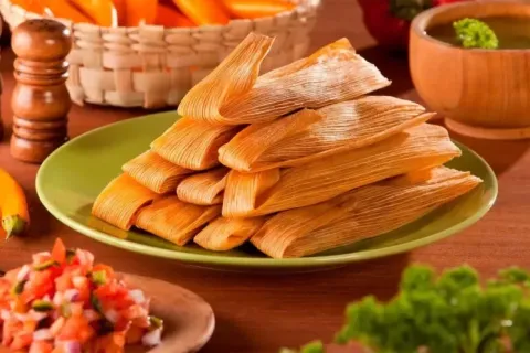 A stack of authentic Peruvian tamales served on a green plate.