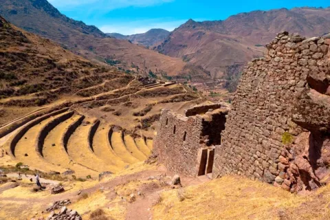 Ancient Inca stone structures and curved agricultural terraces on a mountainside in Pisac, Peru.