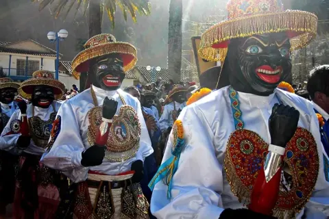 Performers of the Qhapaq Negro dance with traditional masks and decorated hats.