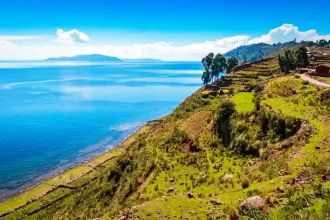High-angle view of the green coastline and clear blue waters of Taquile Island at Lake Titicaca.
