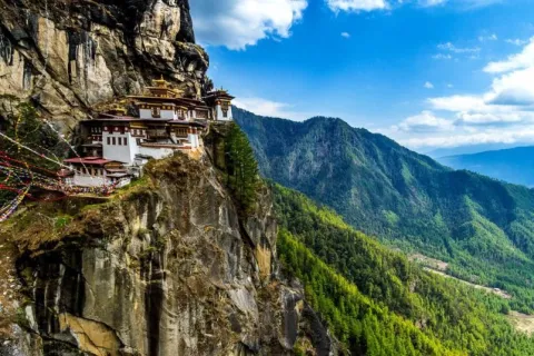 Stunning view of Paro Taktsang (Tiger’s Nest Monastery) built on a cliffside in Bhutan surrounded by green mountains.