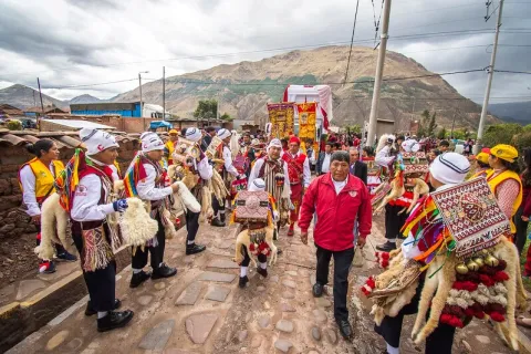 Indigenous people in traditional Andean clothing during a religious procession in the Peruvian highlands.