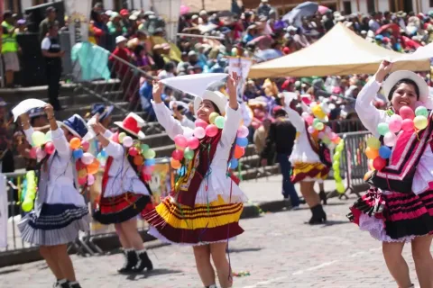 Women dancing with colorful balloons and white hats during the Cusco Carnival.