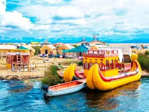 Several large, decorated traditional reed boats docked at a floating island with houses and mountains in the background.