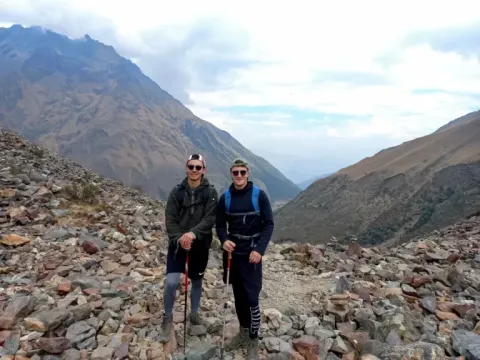 Two male hikers with backpacks posing on a rocky trail in the Salkantay mountains.