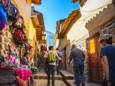 Group of tourists walking through a historic stone-walled street in Cusco near local shops