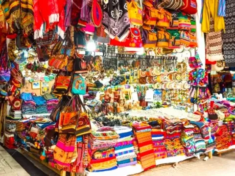 A colorful market stall in Aguas Calientes filled with traditional Andean bags, textiles, and handcrafted souvenirs