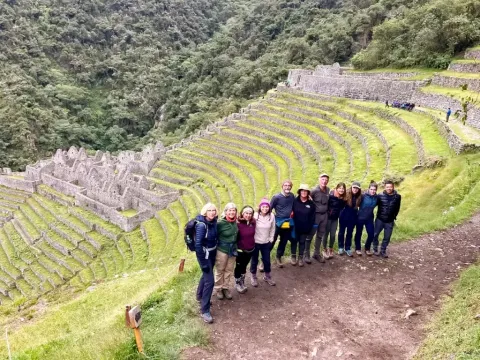 Group of hikers posing in front of the Wiñay Huayna Inca ruins and terraces.