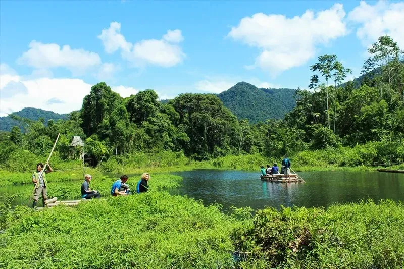 Group of tourists enjoying a raft ride on a calm lake surrounded by the Amazonian jungle.