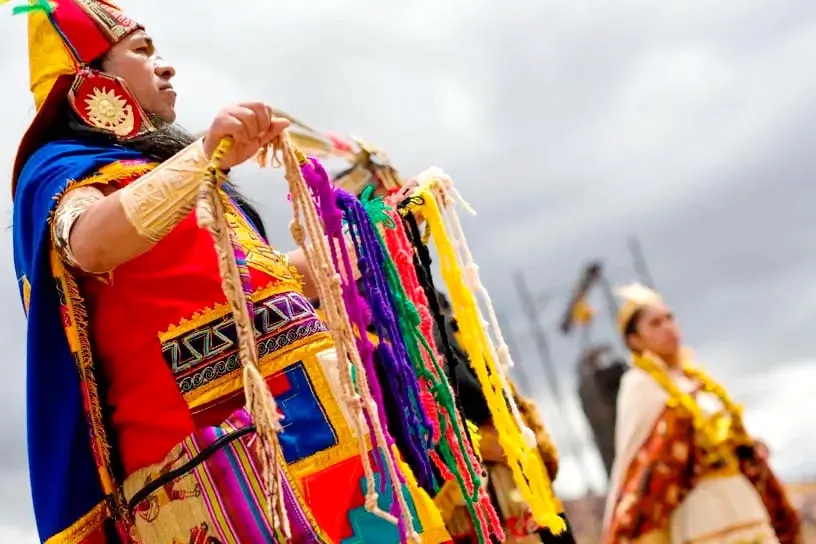The Secret of Inca Quipus Close-up of a person in traditional Andean dress holding a colorful Quipu, the Inca knotted-string record-keeping system.