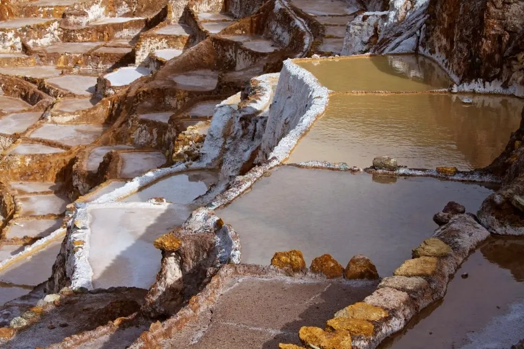 Detailed view of salt water filling the terraced ponds during the traditional salt extraction process in Maras, Peru.