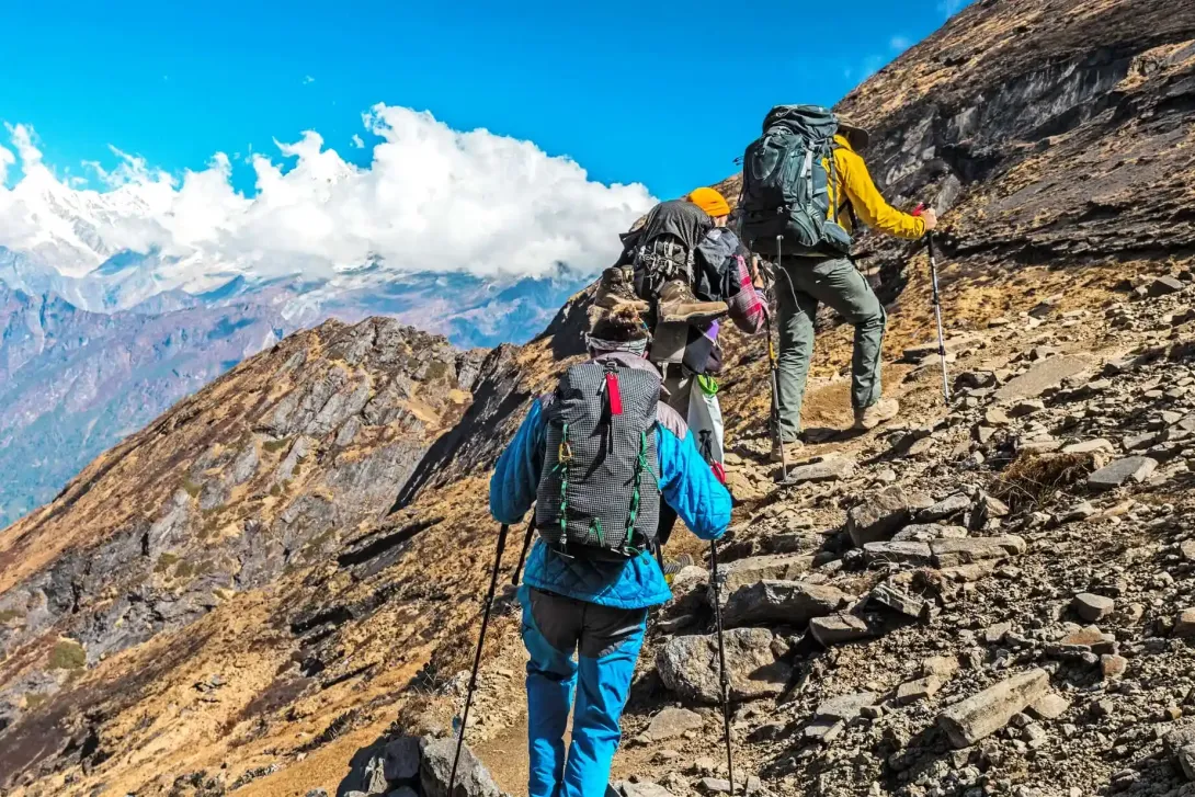 Group of trekkers with hiking poles climbing a rocky mountain path in the Annapurna region of Nepal.