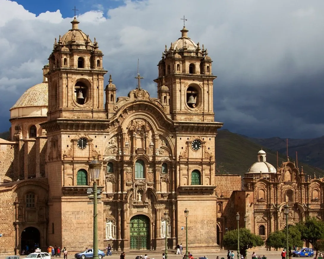 Front view of the Company of Jesus Church (Iglesia de la Compañía de Jesús) in Cusco's Main Square under a cloudy sky.